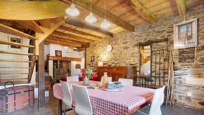 A rustic dining area with a checkered tablecloth, stone walls, wooden beams, and a staircase leading to an upper level. - Chalet La Grange d'Arlette with Mountain View (Sentein)