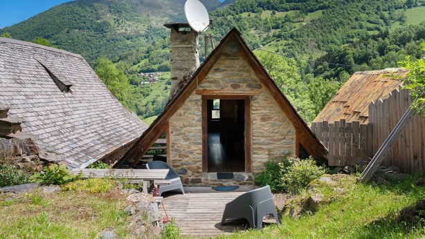 A stone cabin with a satellite dish, wooden deck, and a view of a mountainous landscape. - Chalet La Grange d'Arlette with Mountain View (Sentein)