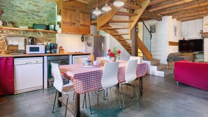 A kitchen with a dining area, wooden beams, a staircase, and a TV in a living room. - Chalet La Grange d'Arlette with Mountain View (Sentein)