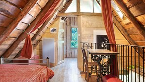 An attic bedroom with a wooden ceiling, a bed, a table with chairs, and a view through a window. - Chalet La Grange d'Arlette with Mountain View (Sentein)