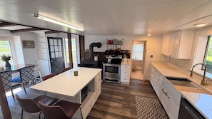 Cocina moderna con una isla central, muebles blancos y vistas al exterior.