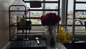 A kitchen counter with a dish rack, a vase with red roses, and dish soap.