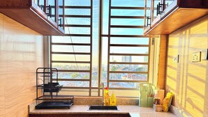 A kitchen with wooden cabinets, a window with blinds, a sink, and a countertop with kitchen utensils.