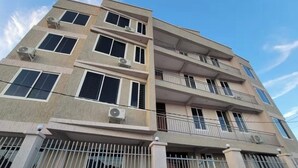 A multi-story building with balconies, air conditioning units, and a gated entrance.