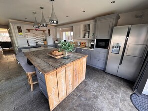 A modern kitchen with a central island, grey cabinets, stainless steel appliances, and pendant lighting. - Cheshire escape. Golf course location. Hot Tub. 4 Ensuite bathrooms. sleeps 10. (Macclesfield)