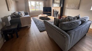 En opholdsstue med sofa, sofabord, fjernsyn og pejs.