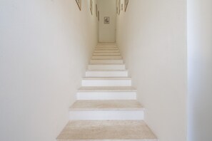 Un escalier menant à un palier où est accrochée une image encadrée au mur.