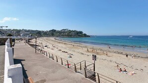 A beach with a promenade, a view of the sea, and buildings in the background. - Holidays in Perros-Guirec – Relaxation, Sea, and Discovery! (Perros-Guirec)