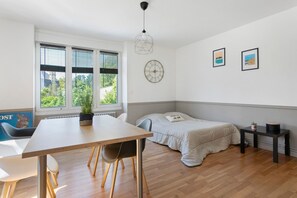 Quarto moderno com cama, mesa de jantar e janela com persianas.