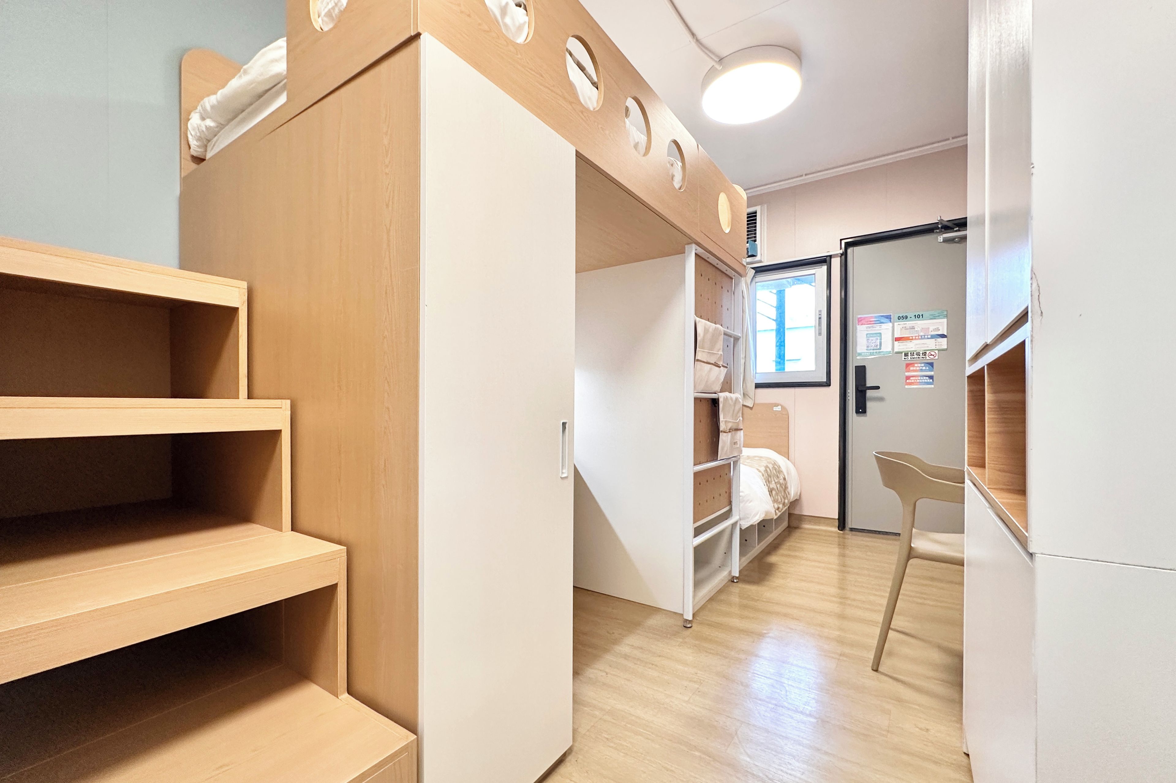 Una habitación moderna y bien iluminada, con estanterías empotradas, una cama con cabecero y una puerta con ventanal.