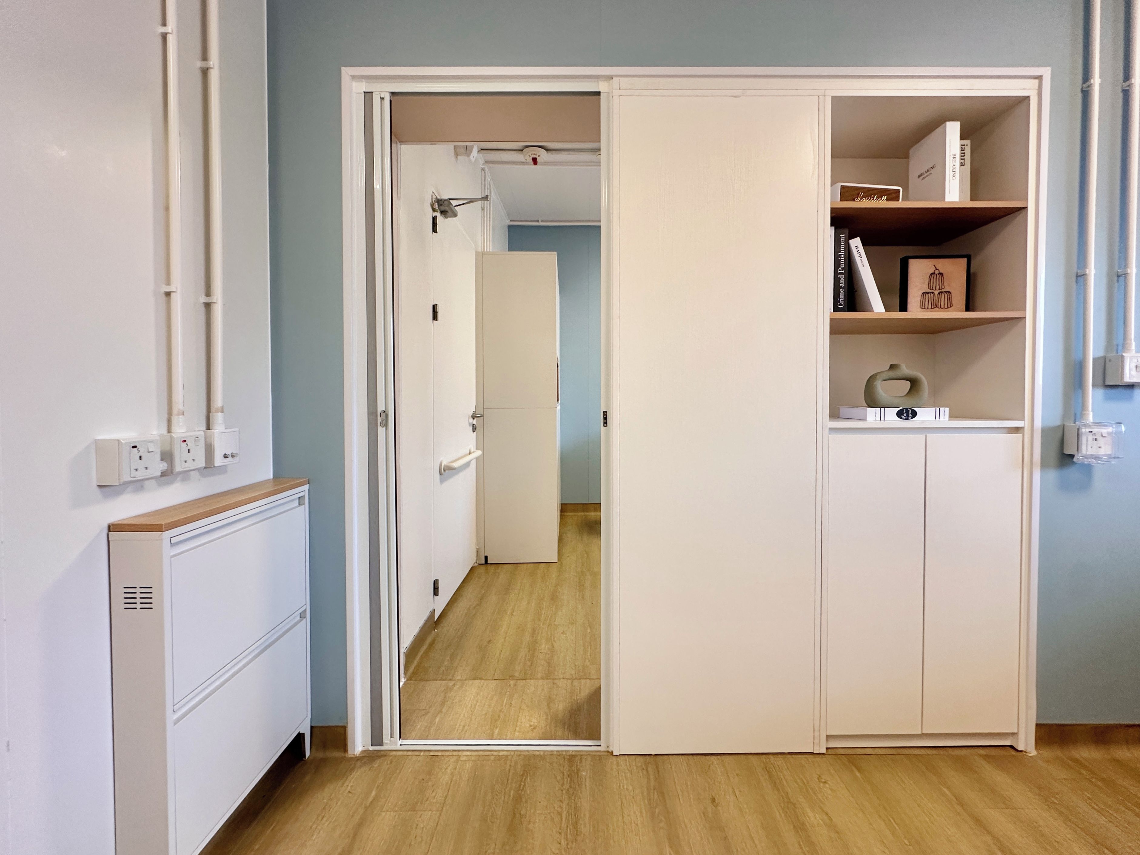 Une pièce avec une armoire blanche, un plancher en bois et une porte qui donne sur une autre pièce.