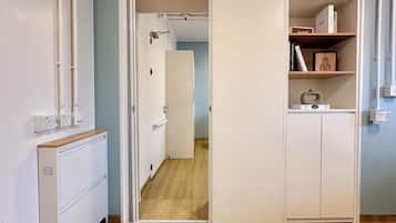 Une pièce avec une armoire blanche, un plancher en bois et une porte qui donne sur une autre pièce.