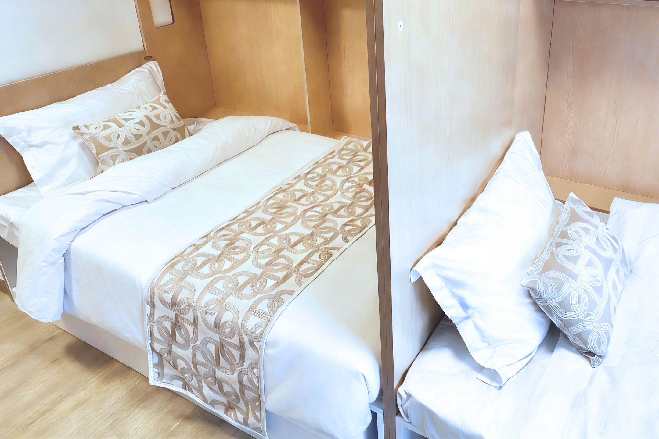 Una cama doble con colcha y almohadas estampadas, cabecera de madera y suelo de madera.