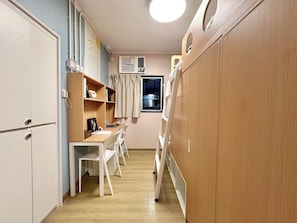 A narrow hallway with a desk, chairs, and a wardrobe. - Runway 1331 - Campus Hostel (Kowloon)