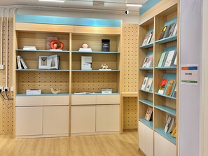A modern library interior with wooden shelves and cabinets, books, and decorative items.