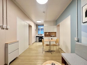A corridor leading to a kitchenette with a dining area, a sofa, and a window with a view.