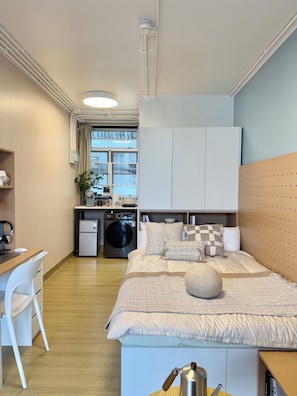 A compact bedroom with a bed, bedside table, and a desk area with a chair. - Runway 1331 - Campus Hostel (Kowloon)