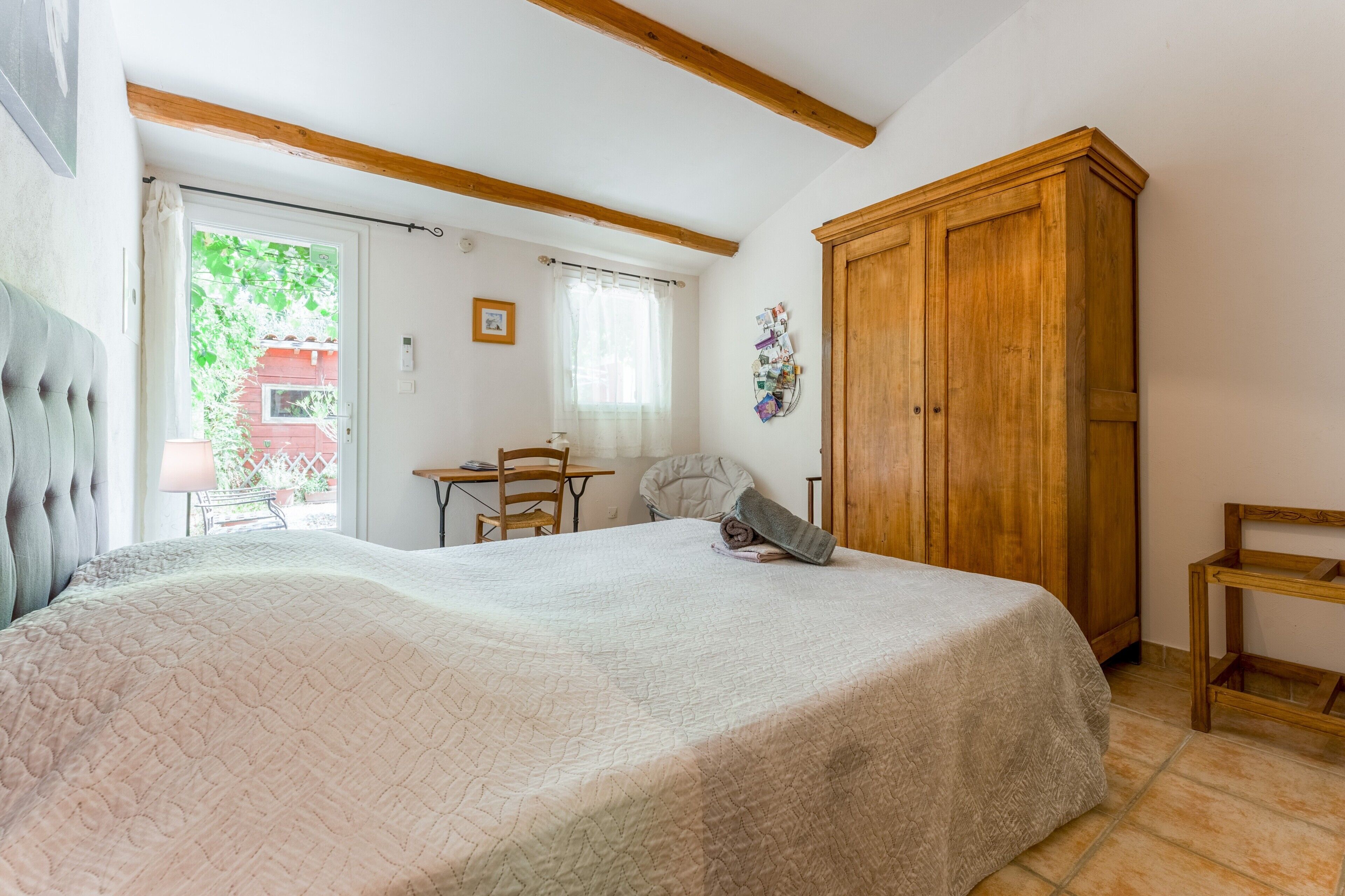 Une chambre à coucher avec un grand lit, une armoire en bois, un bureau et une chaise.