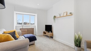 Ein modernes Wohnzimmer mit einer Couch, einem Fernseher und einem Fenster mit Blick.