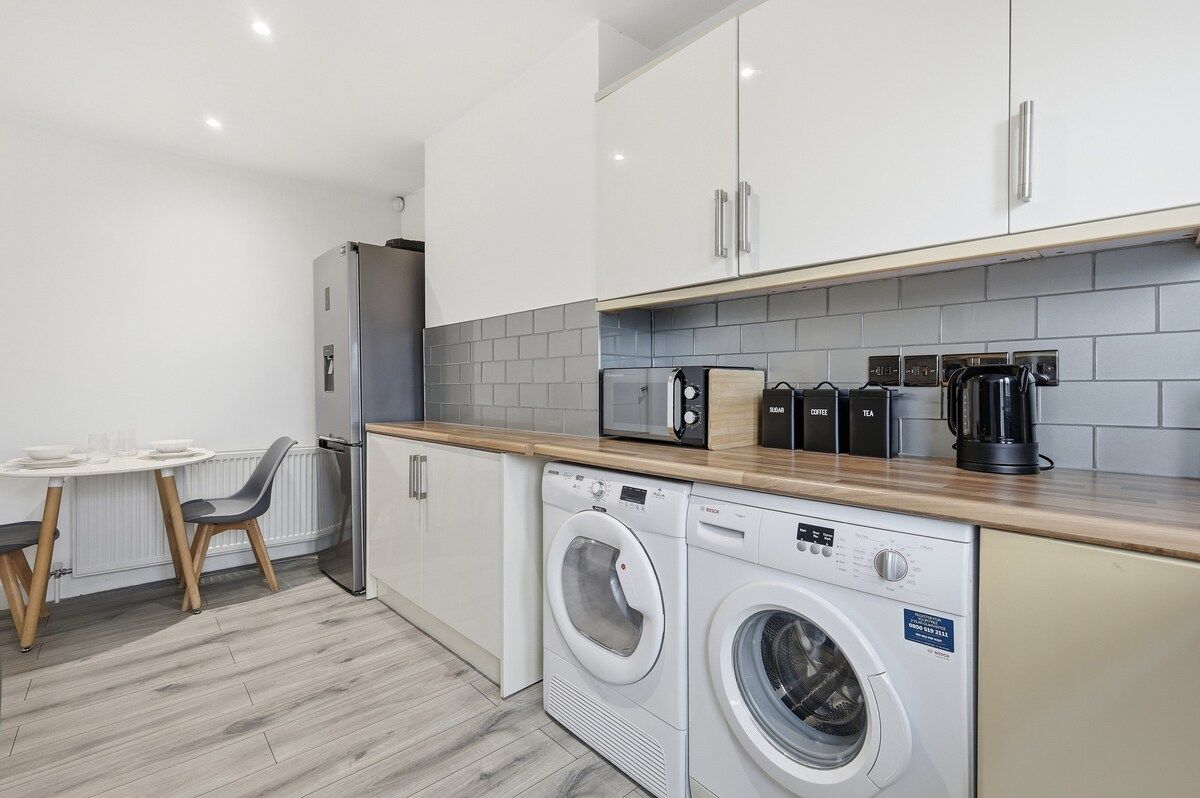 A compact kitchen with a washing machine, a coffee maker, and a microwave.