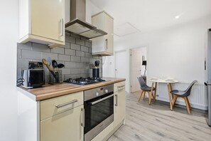Et moderne køkken med gaskogeplade, ovn og spiseområde med bord og stole.