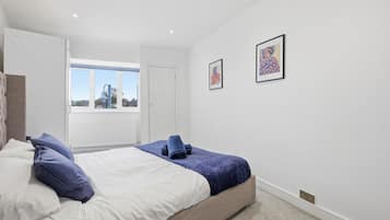 A bedroom with a bed, a window, and two framed pictures on the wall.