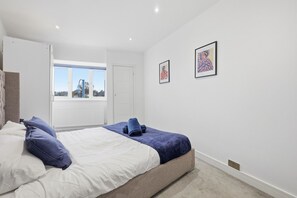A bedroom with a bed, a window, and two framed pictures on the wall.