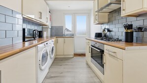 Eine kleine Küche mit Waschmaschine, Backofen und Blick ins Freie.