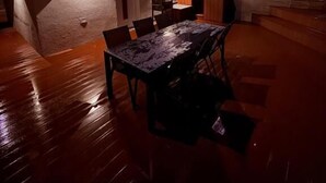 Un área de comedor al aire libre con una mesa y sillas, una pequeña cocina y una escalera que lleva a un nivel superior.