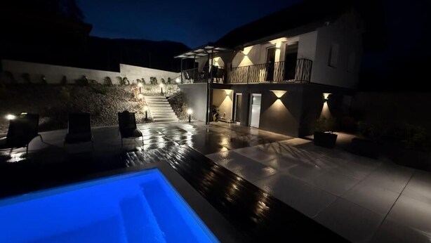 Una casa moderna con piscina, un patio cubierto y una escalera que lleva a un segundo piso.