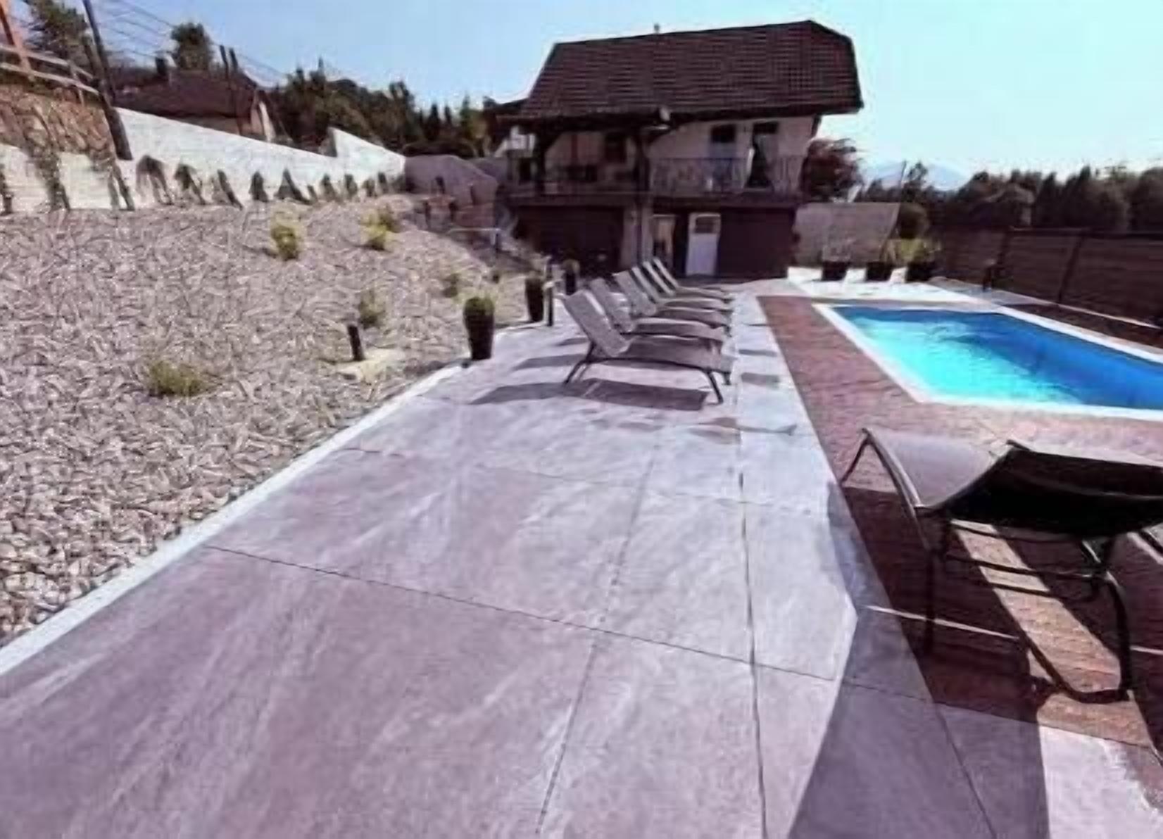 Ein Poolbereich mit Liegestühlen, einem Schwimmbecken und einem Haus im Hintergrund.