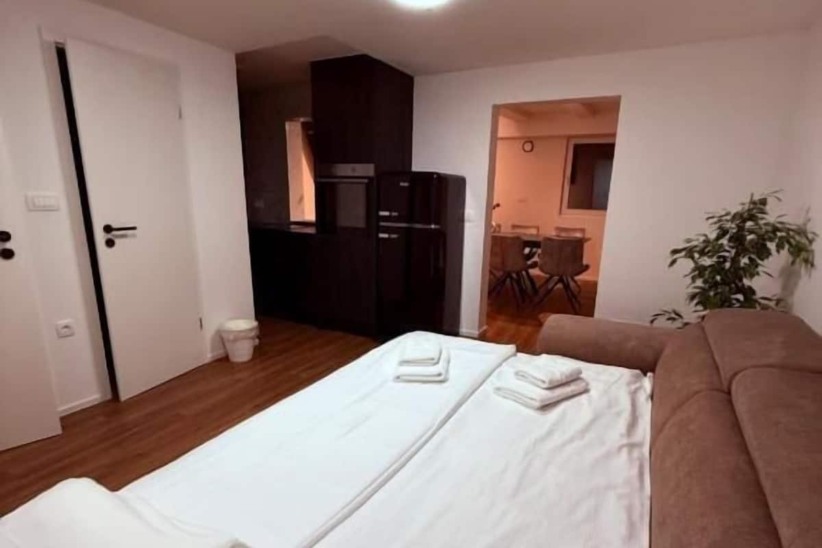 Ein Hotelzimmer mit Bett, einer Couch, einer Küchenzeile und einem durchgegangenen Tür erkennbaren Badezimmer.
