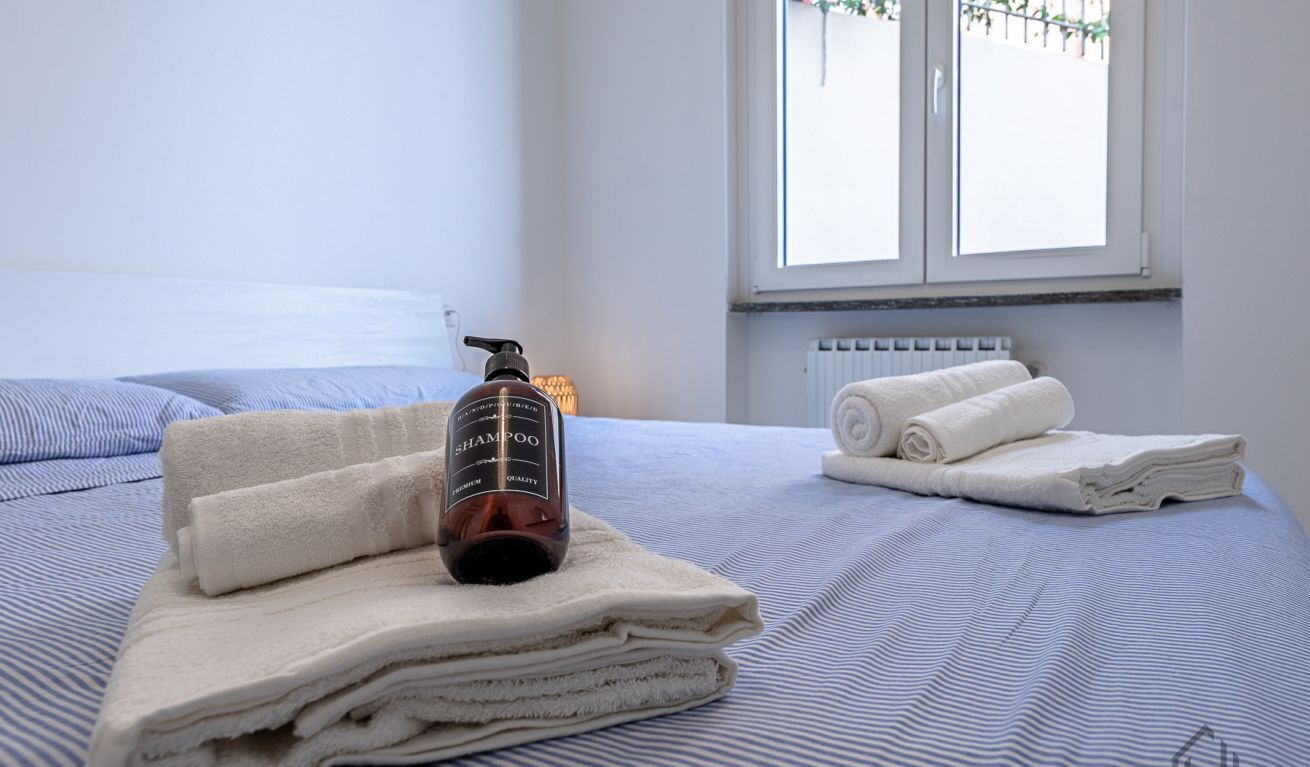 Un letto rifatto con asciugamani piegati e una bottiglia di shampoo.