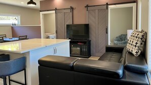 A modern living space with a kitchen area, a dining table, a sofa, and a television.