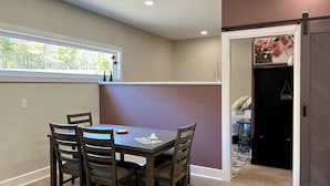 A dining area with a table and chairs, a window with a view, and a door leading to another room.