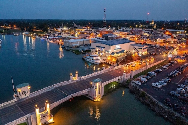 A waterfront town with a bridge, docked boats, and a parking area.