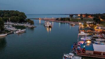 A marina with boats docked, a lighthouse in the distance, and a docked yacht.