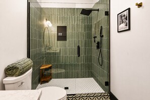 A modern bathroom with a glass-enclosed shower, a toilet, and a small wooden stool. - Reasonable Doubt --- Vibrant, unforgettable loft in Downtown Port Clinton (Port Clinton)