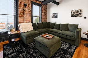 A modern living room with a sectional sofa, a coffee table, and a small side table.