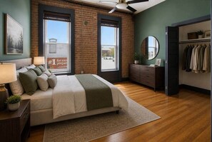 A bedroom with a bed, dresser, and a closet with hanging clothes.
