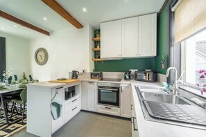 Uma cozinha moderna com armários brancos, forno embutido, micro-ondas e pia.