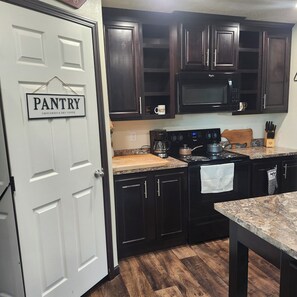 A kitchen with dark wood cabinets, a white door labeled 'PANTRY,' a microwave, and a stove. - 4 Bedroom, 2 Bath Historical Homestead on the Bighorn River- Longwell Boat Ramp. (Thermopolis)