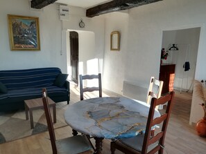 Een woonkamer met een bank, eettafel, stoelen, een schilderij, een klok en een spiegel.