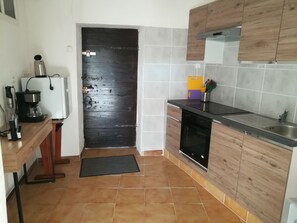 Una cucina compatta con macchina da caffè, frigorifero, lavello e pensili in legno.