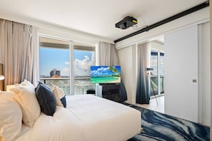 A hotel room with a bed, a TV, a balcony with a city view, and a projector. - W Residences | High Floor 1-Bed | Ocean View (Fort Lauderdale)