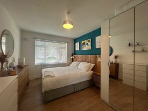 A bedroom with a bed, a bedside table, a mirror, a window with blinds, and a wardrobe. - Charming Sandymount APT Sleeps 4 (Dublin)