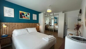 Een hotelkamer met een bed, nachtkastje, spiegel en kunst aan de muren.