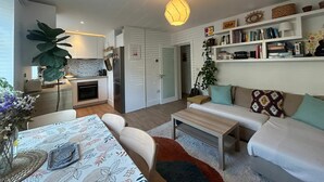 Een moderne woonruimte met keuken, eethoek en een gezellige zithoek met een boekenkast.