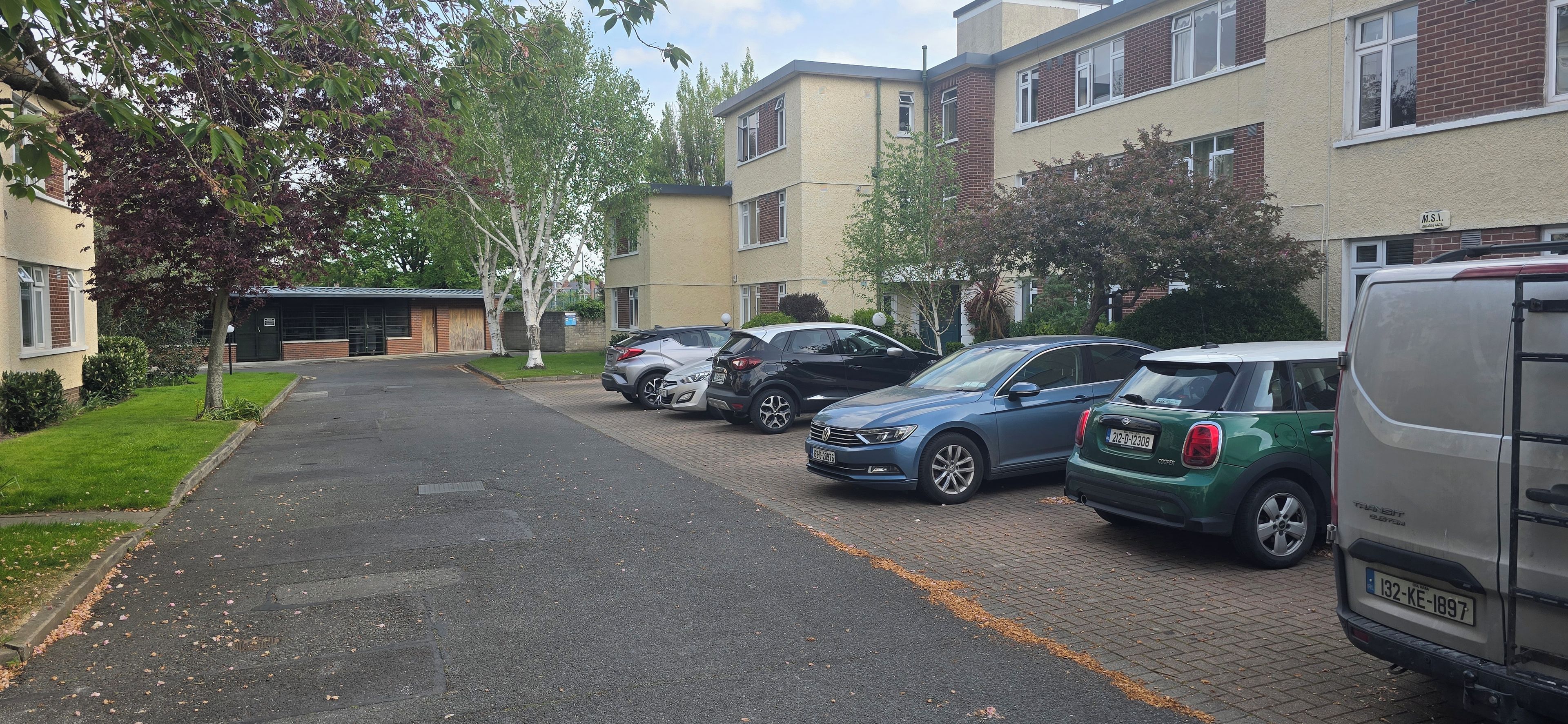 A residential street with parked cars and a building with a garage.