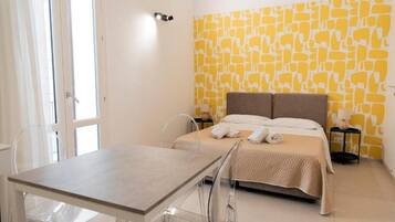 A bedroom with a bed, a table, chairs, and a wall with a yellow pattern.